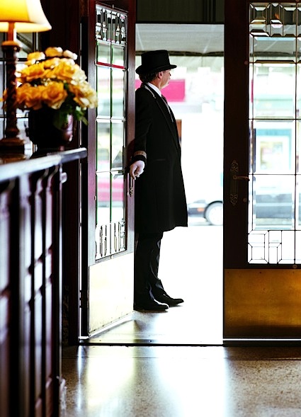 Doorman holding hotel door open, view from lobby