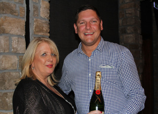 Delia Aston  receives a bottle of champagne from Ben Bouldin .