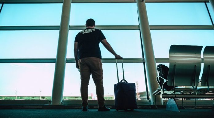 IATA: Arriving at the Airport ‘Ready to Fly’ One Step Closer A man looks out of the airport and has a suitcase in hand, and seems like he is ready to fly or board his plane