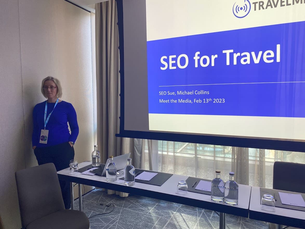 SEO for Travel with Sue Palmer session with Sue in a blue top and black pants and a screen in blue and white 