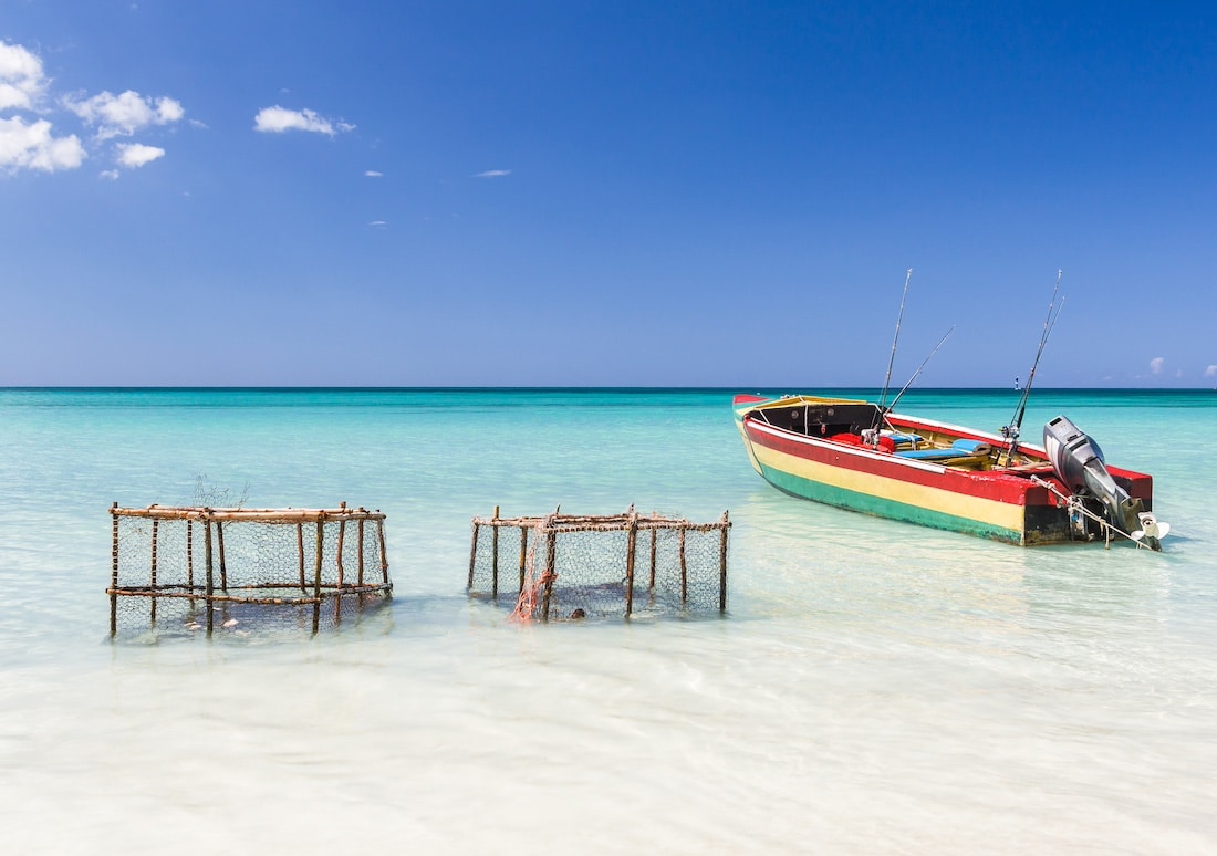 Turquoise water in barbados, in the caribbean, with a red fishing boat and some crab catching cases