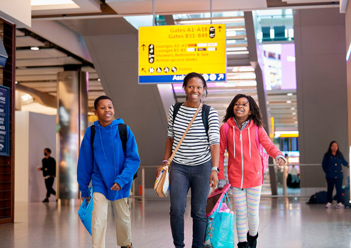 A mother and two children walking through London Heathrow Airport Terminal 2.